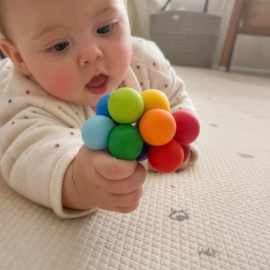 Baby med kuglerangle i primaerfarver