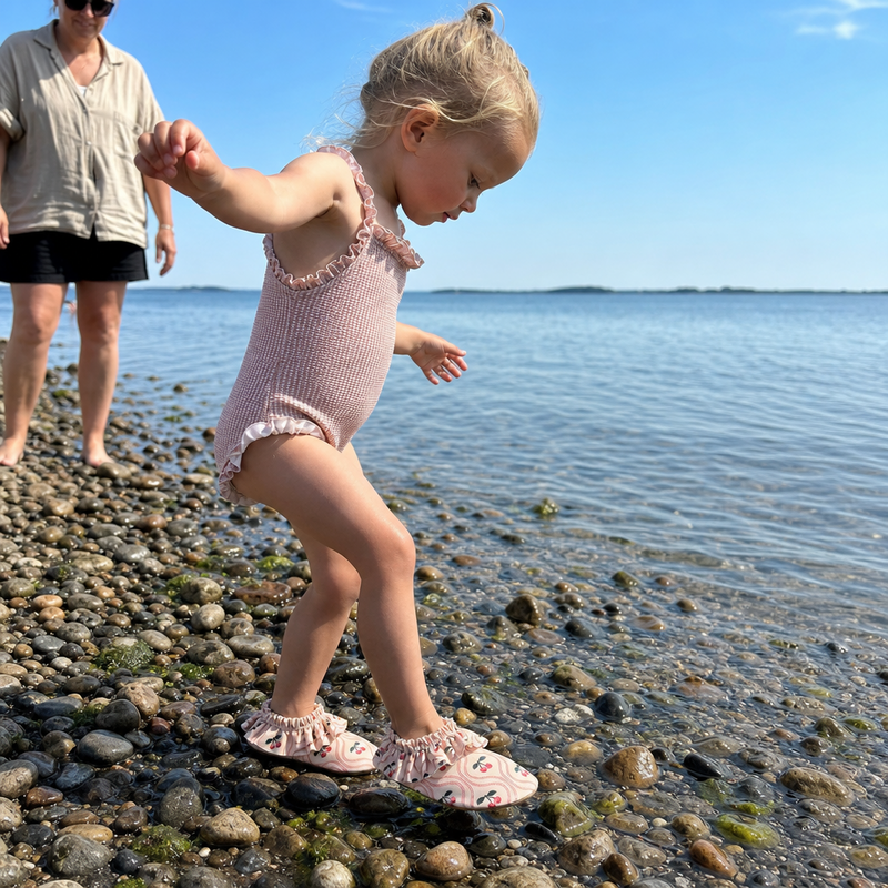 Barn leger i vandet i badesko med cherry pink motiv
